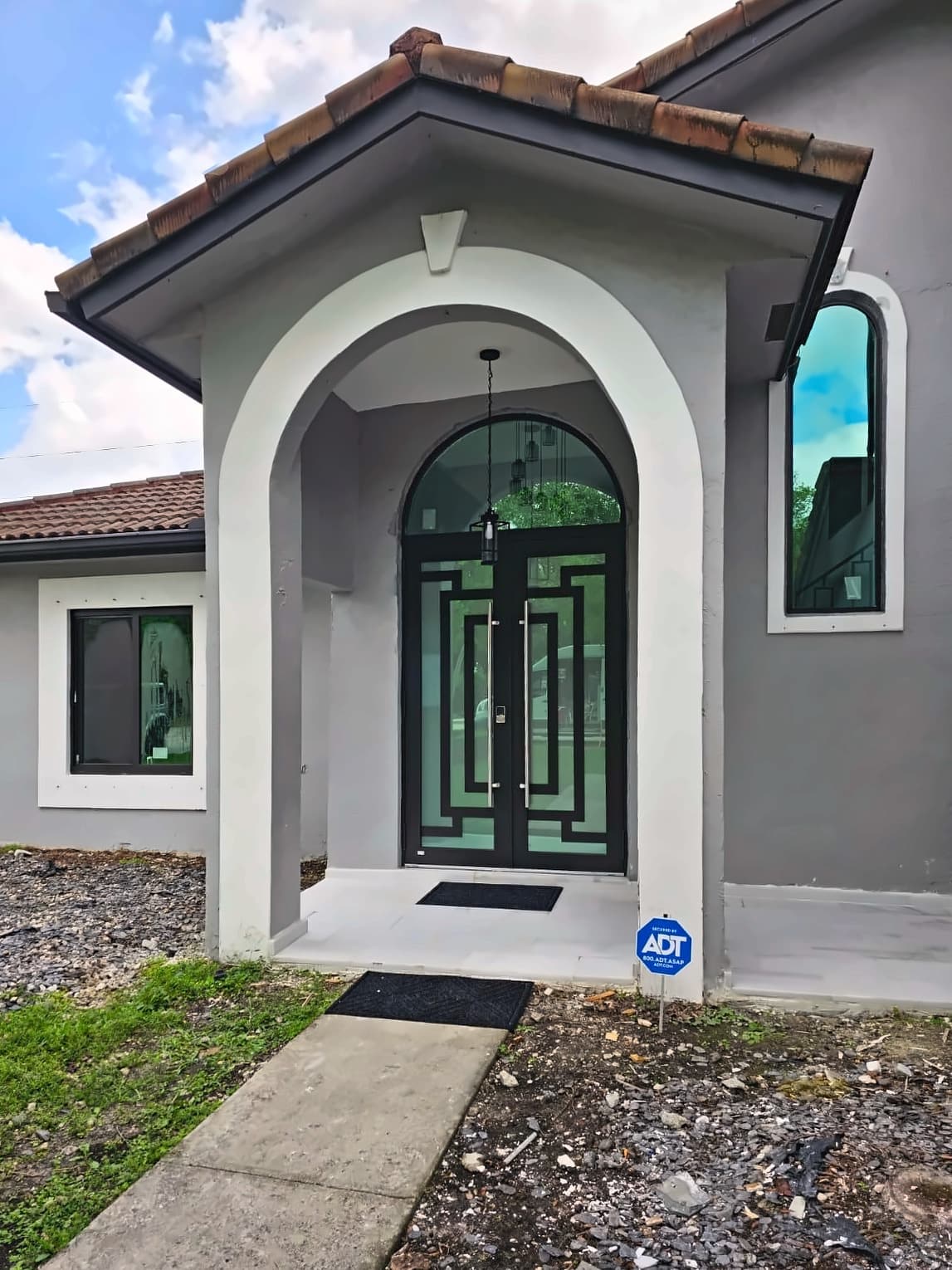 Arched glass double entry doors under a covered front porch