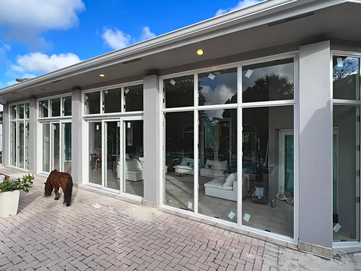 White-framed sliding glass doors and windows along a paver patio